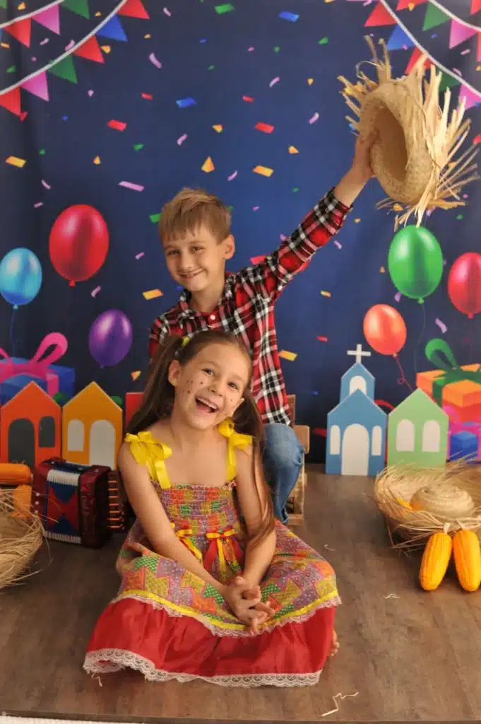 Deux enfants déguisés, souriants et jouant dans un décor festif avec ballons et confettis, lors d'un événement spécial.